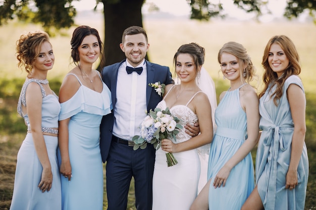 элегантная и стильная невеста вместе со своими четырьмя друзьями в синих платьях и ее мужем