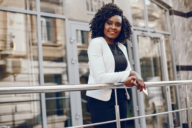 elegant and stylish dark-skinned girl with curly hair and in a white jacket standing 