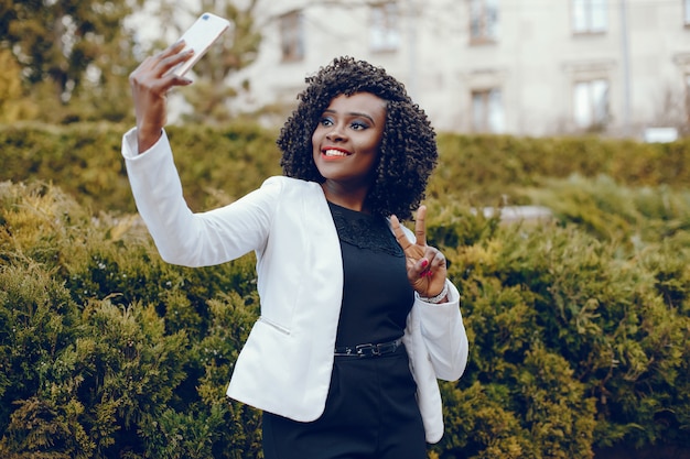 elegant and stylish dark-skinned girl with curly hair and in a white jacket walking around