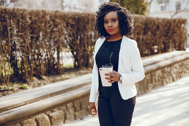 elegant and stylish dark-skinned girl with curly hair and in a white jacket walking around