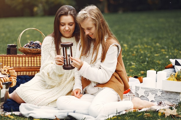 Ragazze eleganti e alla moda che si siedono in un parco di autunno