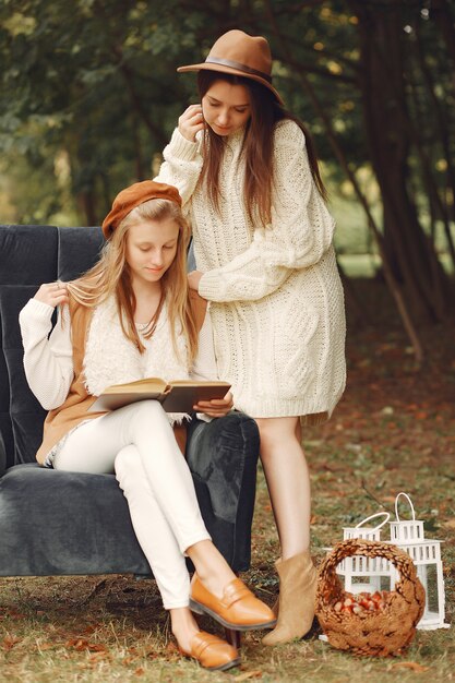 Elegant and stylish girls sitting on a chair in a park reading a book