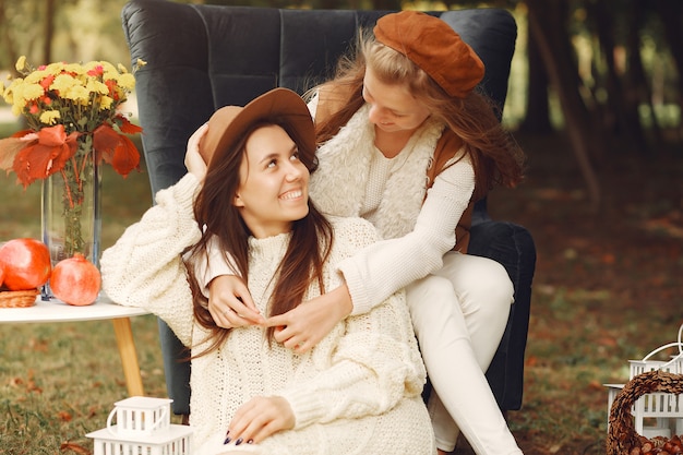 Elegant and stylish girls sitting on a chair in a park