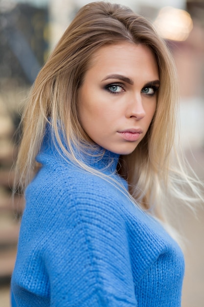 Elegant stylish woman with charming smile looks into camera. Girl in blue outfit posing on street in spring