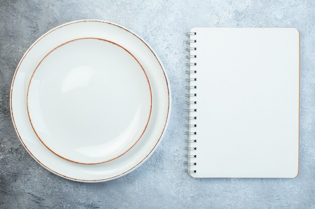 Elegant white plates and notebook on gray surface with distressed surface with free space