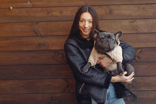 Foto gratuita donna elegante in una giacca nera con bulldog nero