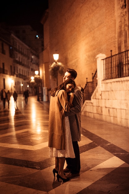 Elegant woman embracing with young man on promenade at night