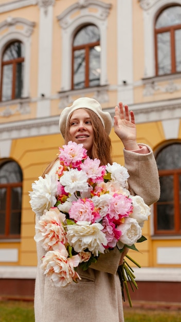 Elegant woman holding bouquet of flowers outdoors in the spring