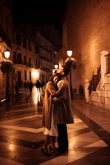 夕方に遊歩道で若い男と抱擁する優雅な女性