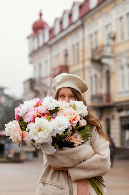 Free photo elegant woman outdoors holding bouquet of flowers in the spring