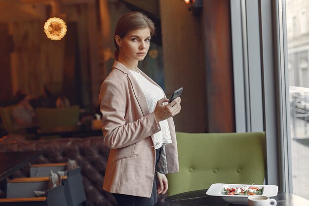 Elegant woman in a pink jacket spend time in a cafe