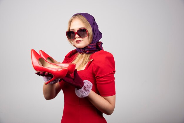 Elegant woman in red dress holding pair of heels. 