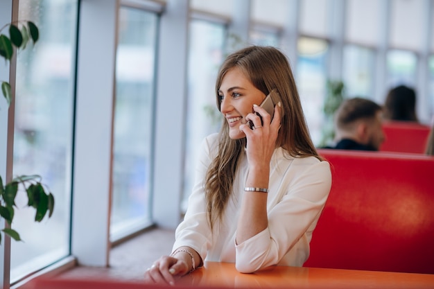 Donna elegante in un ristorante sorridente e parlare su un cellulare