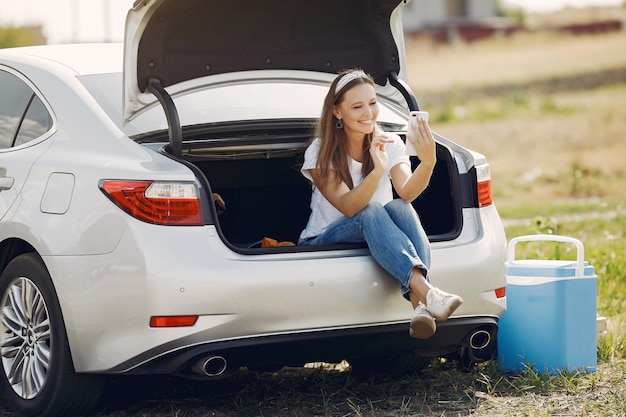 Free photo elegant woman sitting in a trunk with mobile phone