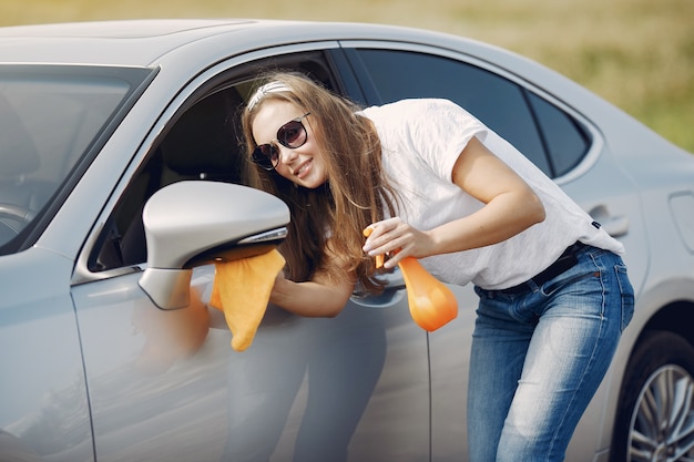 Elegant woman wipes the car with a rag