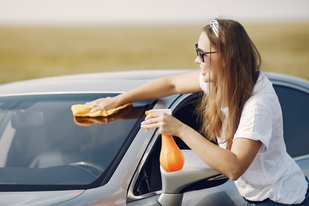 エレガントな女性がぼろで車を拭く