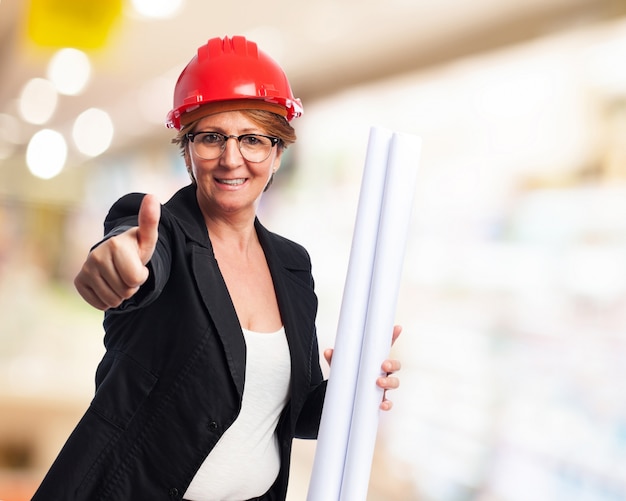 Elegant woman with blueprints and thumb up