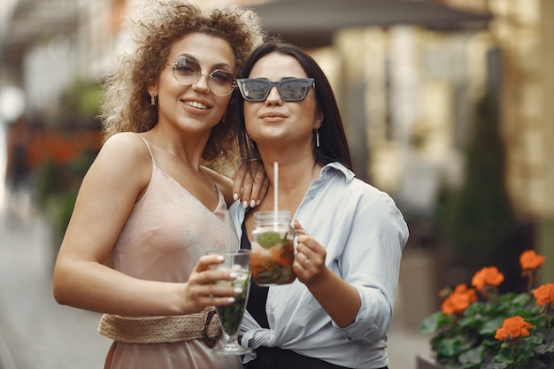 Elegant women drinks cocktails in a summer city