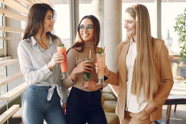 Elegant women standing in a cafe and drinking a cocktails