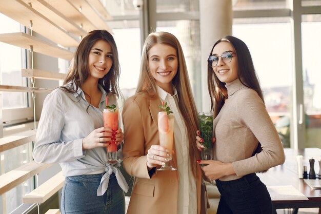 Elegant women standing in a cafe and drinking a cocktails