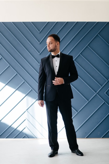 Elegant young handsome man in classic black costume. Studio fashion portrait.