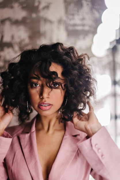 Elegant young lady in pink jacket looking at front