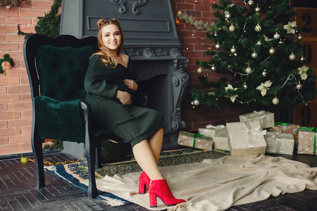 Elegant young lady sitting near Christmas tree