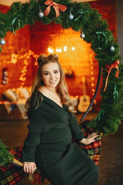 Elegant young lady sitting near Christmas tree