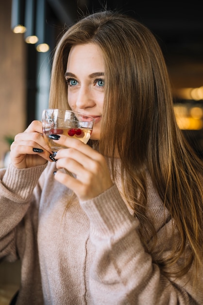 Элегантная молодая женщина улыбается, пить из чашки в кафе
