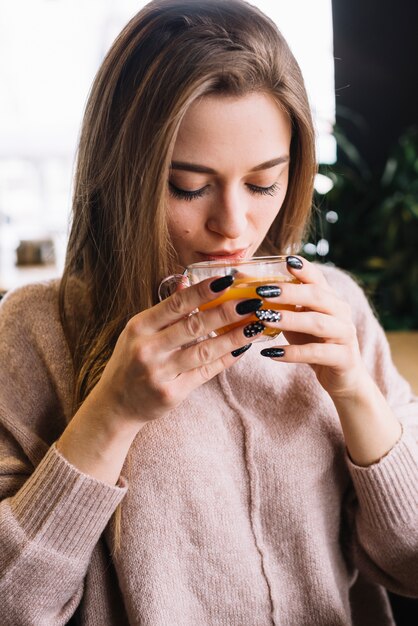 Elegant young woman drinking from cup in cafe