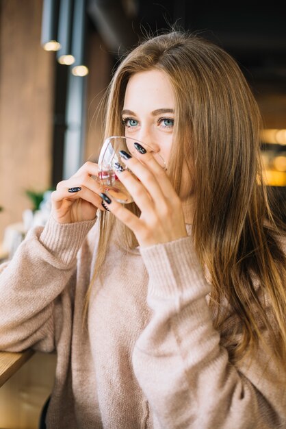 エレガントな若い女性がカフェのカップから飲む