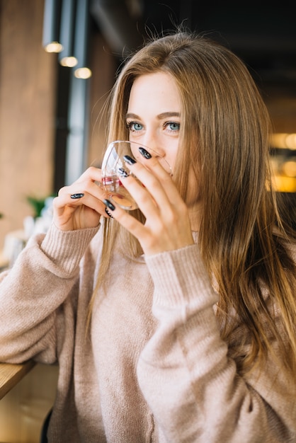 Элегантная молодая женщина пьет из чашки в кафе