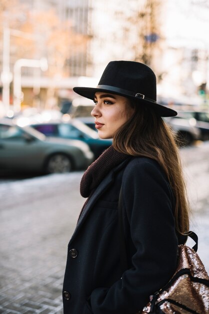 帽子とコートの路上でエレガントな若い女性