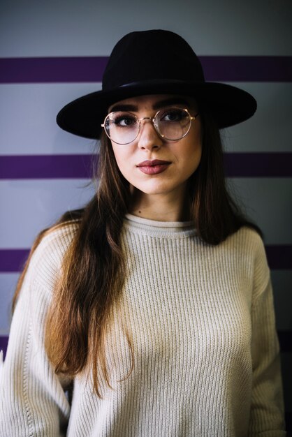 Elegant young woman in hat and eyeglasses