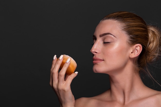 Elegant young woman holding orange