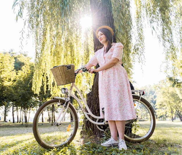 自転車でポーズをとってエレガントな若い女性