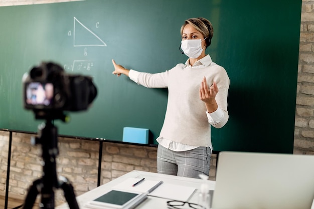 Бесплатное фото Учитель начальной школы указывает на классную доску во время преподавания математики онлайн во время эпидемии coivd-19.