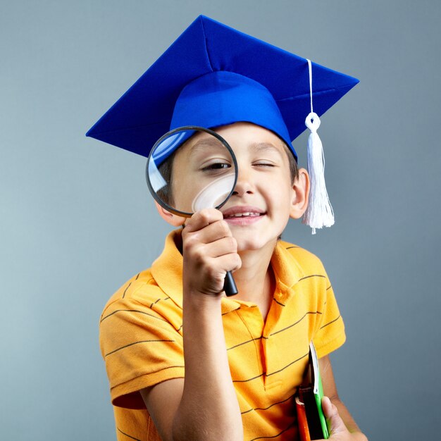 Elementary student with magnifying glass and graduation cap