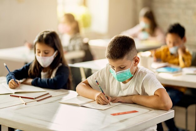 コロナウイルスの流行後、学校に戻って保護フェイスマスクを持っている小学生