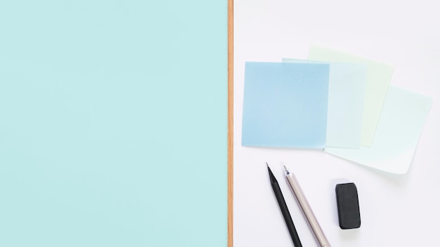 Elevated view of adhesive notes; pen; pencil and eraser on desk