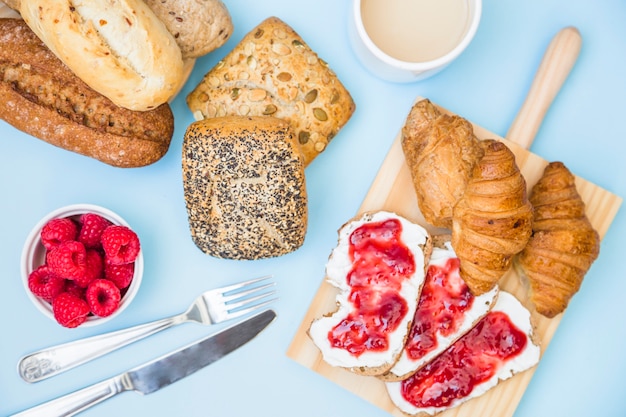 Elevated view of baked food with strawberries and tea on blue background