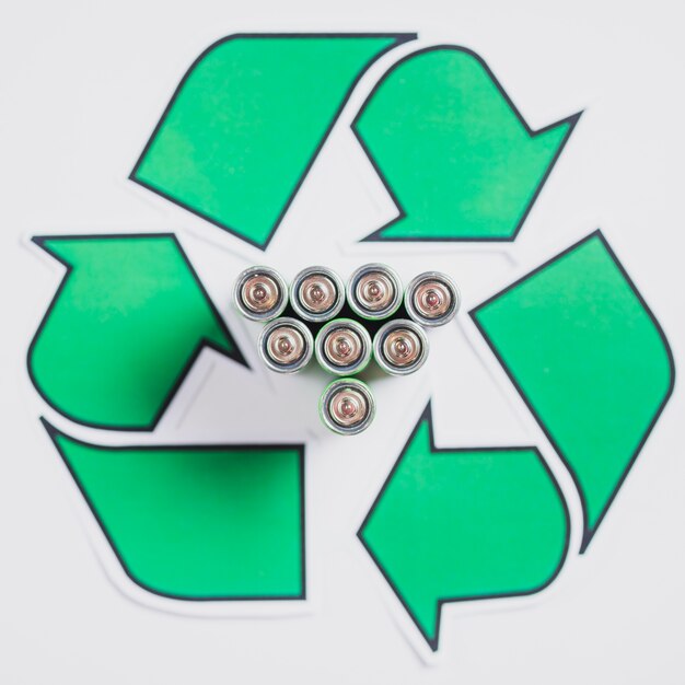 Elevated view of batteries in recycle symbol on white backdrop