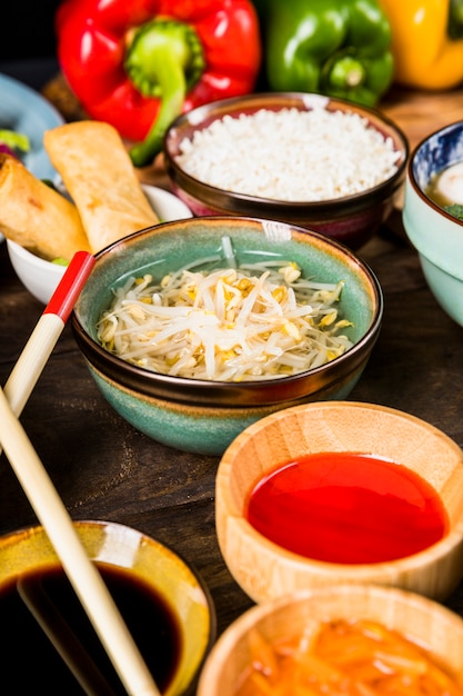 Free photo an elevated view of beans sprouts and sauces bowl of wooden desk