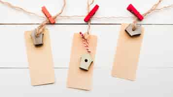 Free photo an elevated view of birdhouse tag tied with cloth pegs on white wooden plank