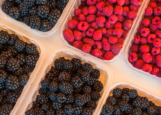 An elevated view of blackberries and raspberries in plastic crate