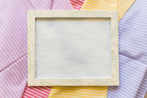 Elevated view of blank frame on colorful stripes pattern textiles