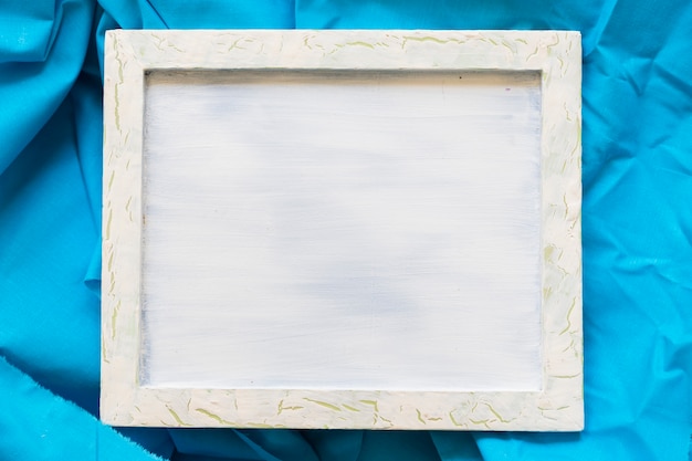 Elevated view of blank picture frame on blue textile