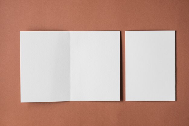 Elevated view of blank white papers on brown backdrop
