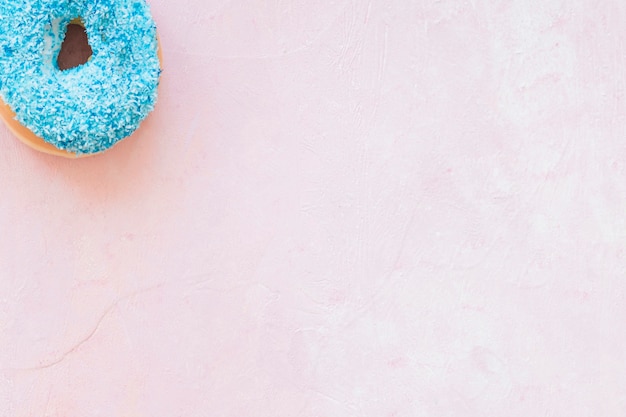 Elevated view of blue donut at the corner of pink background