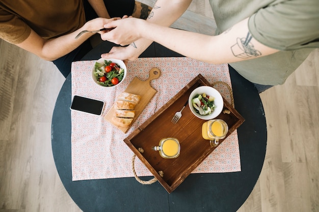 Elevated view of breakfast and mobile phone on table in front of men